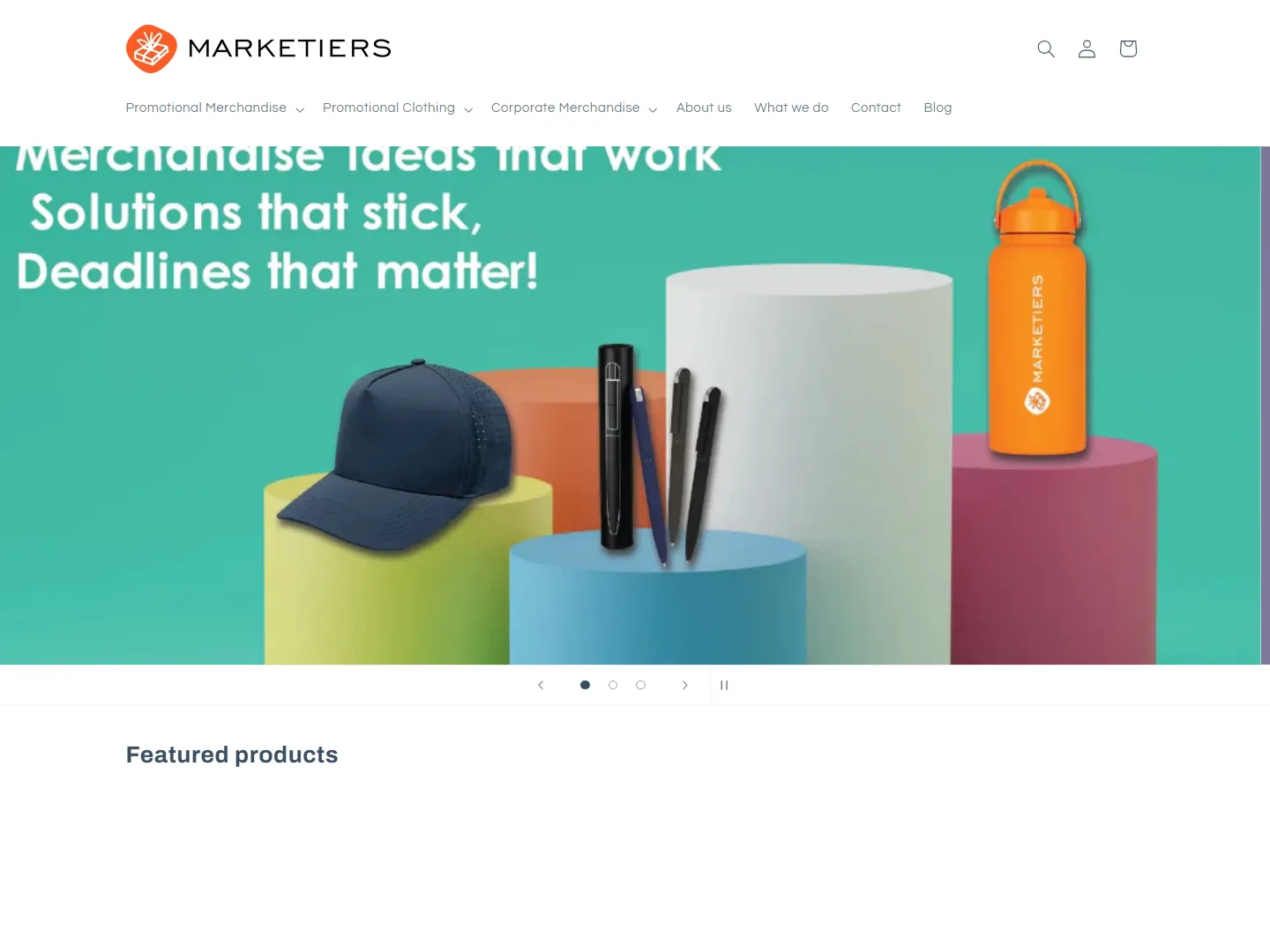 The Marketiers website, showing branded promotional merchandise including a cap, pens and a drink bottle